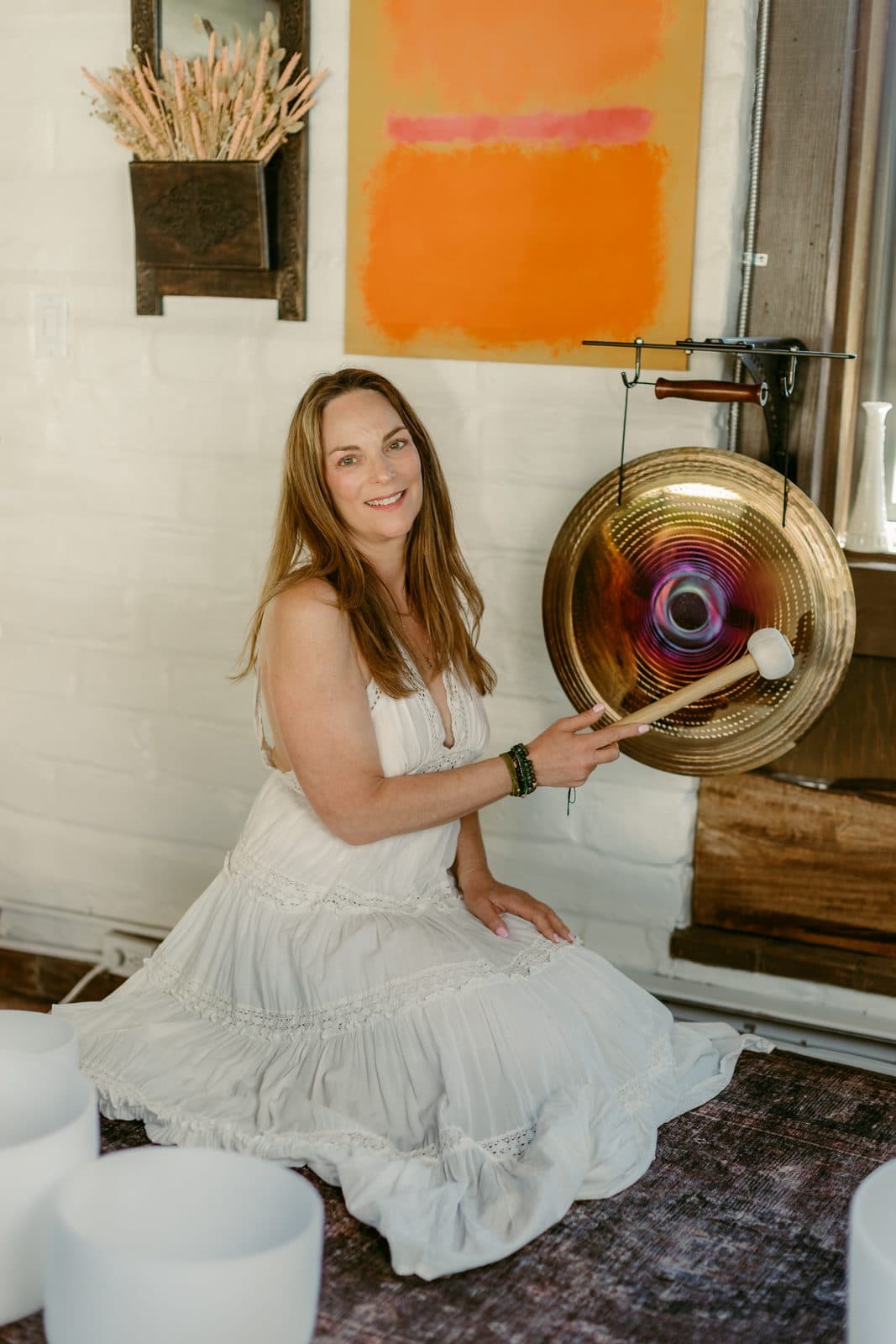 Miki seated on the floor beside a large gong, striker in hand