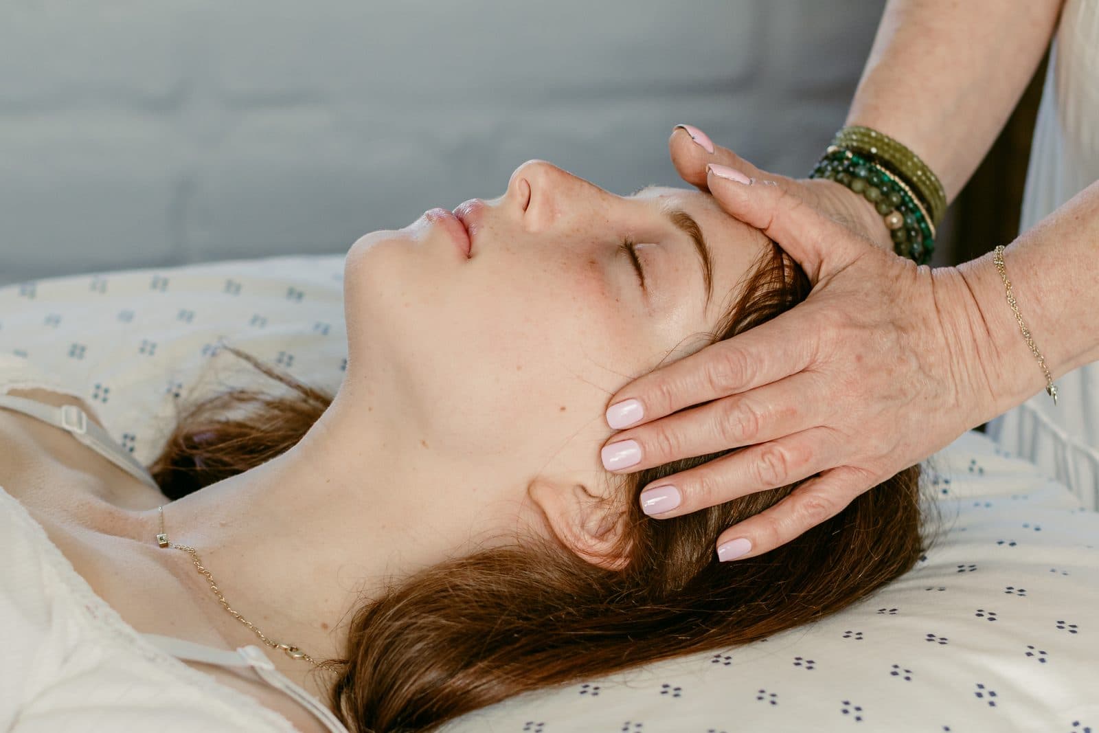 Miki's hands resting lightly on either side of a client's head, the client's eyes closed